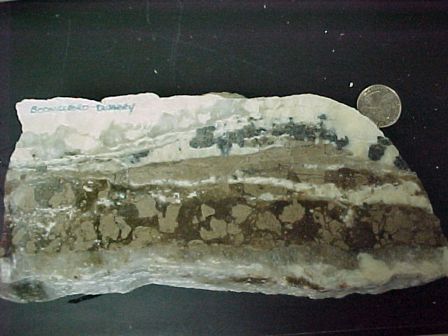 Vein deposit showing brecciation of limestone host rock, and barite, calcite, and sphalerite minerals. 